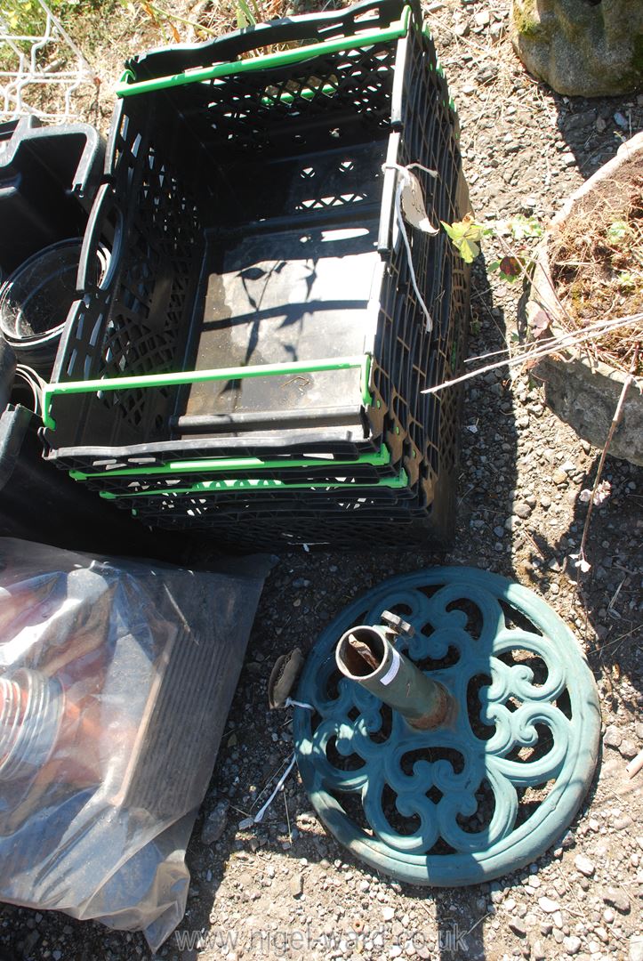 A metal garden umbrella base and four stackable crates.