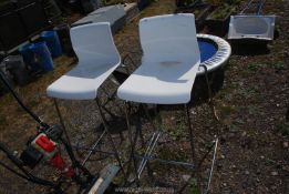 A pair of white plastic and chrome bar stools.