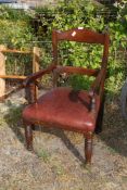 A dark wood armchair with faux leather seat.