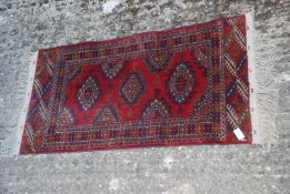 A red and green prayer rug with fringing, 40" x 20".