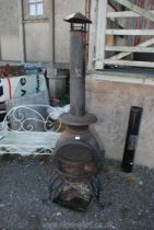 A cast iron chiminea with barbecue shelf and chimney,