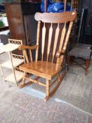 A contemporary hardwood Rocking Chair having a lath back, turned legs, arm and back supports.