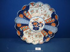 An oriental plate with petal edges and scenic panels between patterned sections with floral centre,