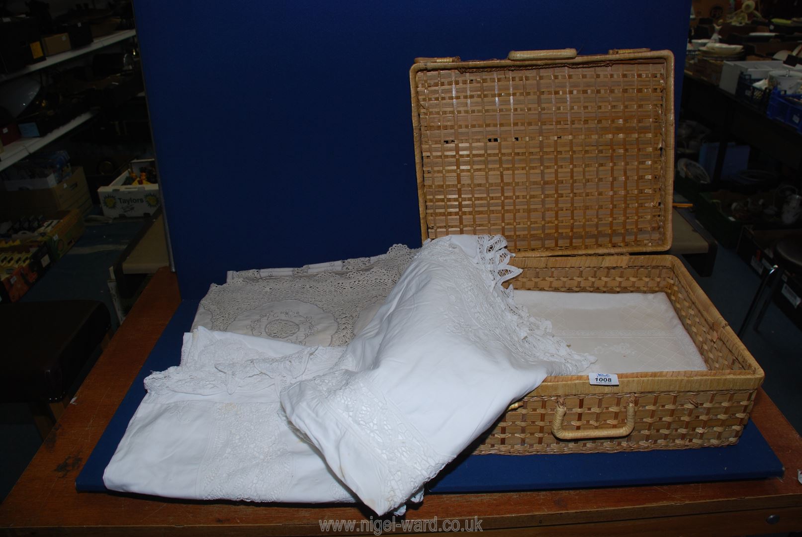 Five large vintage linen tablecloths, some having embroidery or lace edges, etc., in picnic basket.