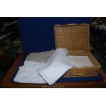 Five large vintage linen tablecloths, some having embroidery or lace edges, etc., in picnic basket.