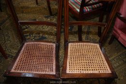 A pair of cane seated darkwood bedroom chairs having light and darkwood stringing.