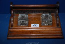 A darkwood Standish with carved detail to the back and two square glass inkwells with swivel tops,