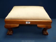 A cream upholstered footstool on ball and claw feet, 18 1/4" wide x 14 1/4" deep x 10" high.