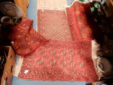 Three small hearth rugs all with border patterns and fringing and on red ground: one with all over