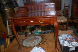 A dark Mahogany writing Table standing on canted cabriole legs and having a frieze drawer with drop