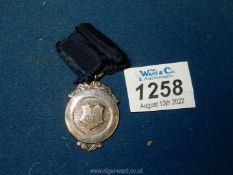 A hallmarked silver medallion on blue braid, engraved verso "O. Owen 2nd All Round, 2nd Section J.A.