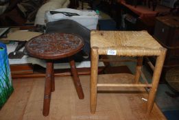 An old carved tripod stool with circular top, plus a grass seated stool.