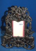 A cast metal embossed, freestanding photograph frame with cherub decoration to top,