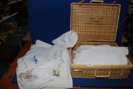 A picnic basket containing small and medium linen tablecloths,