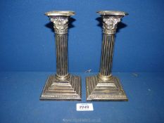 A pair of epns candlesticks with Corinthian columns stems and Acanthus leaf detail.