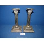 A pair of epns candlesticks with Corinthian columns stems and Acanthus leaf detail.