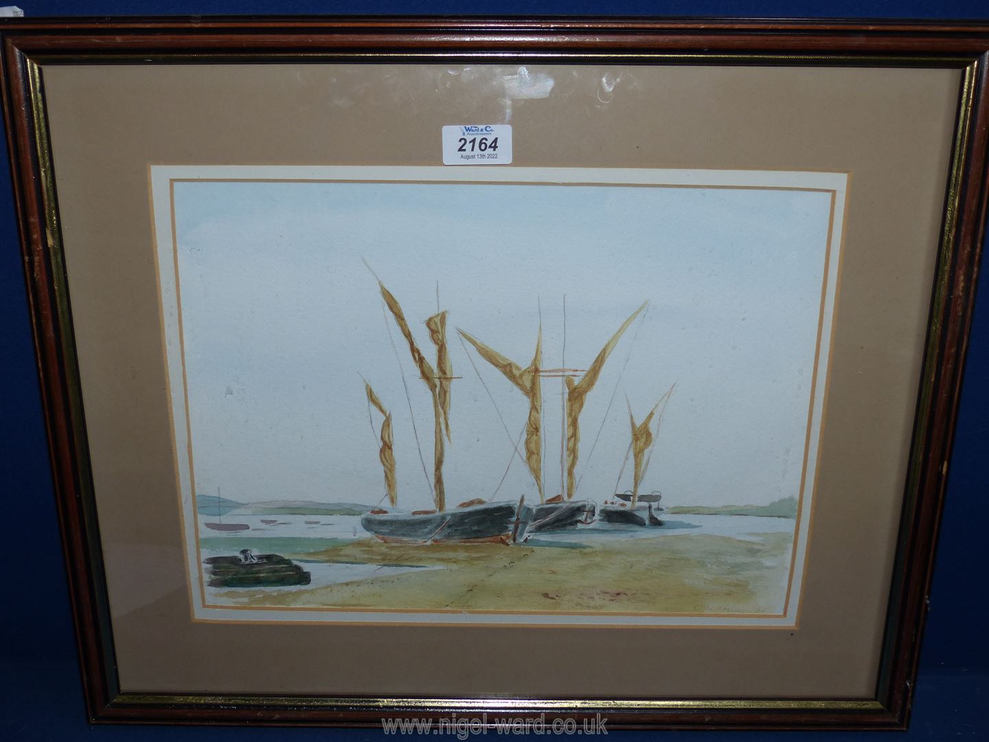 A framed and mounted watercolour depicting moored boats at low tide, signed lower right 'C. Heames'.