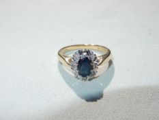 An 18ct gold lady's cluster ring with a central oval sapphire surrounded by 8 illusion diamonds