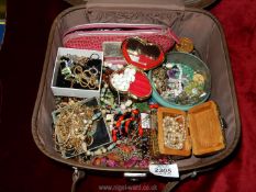 A brown vanity case full of assorted jewellery, beads, gold coloured chains necklaces, etc.