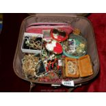 A brown vanity case full of assorted jewellery, beads, gold coloured chains necklaces, etc.