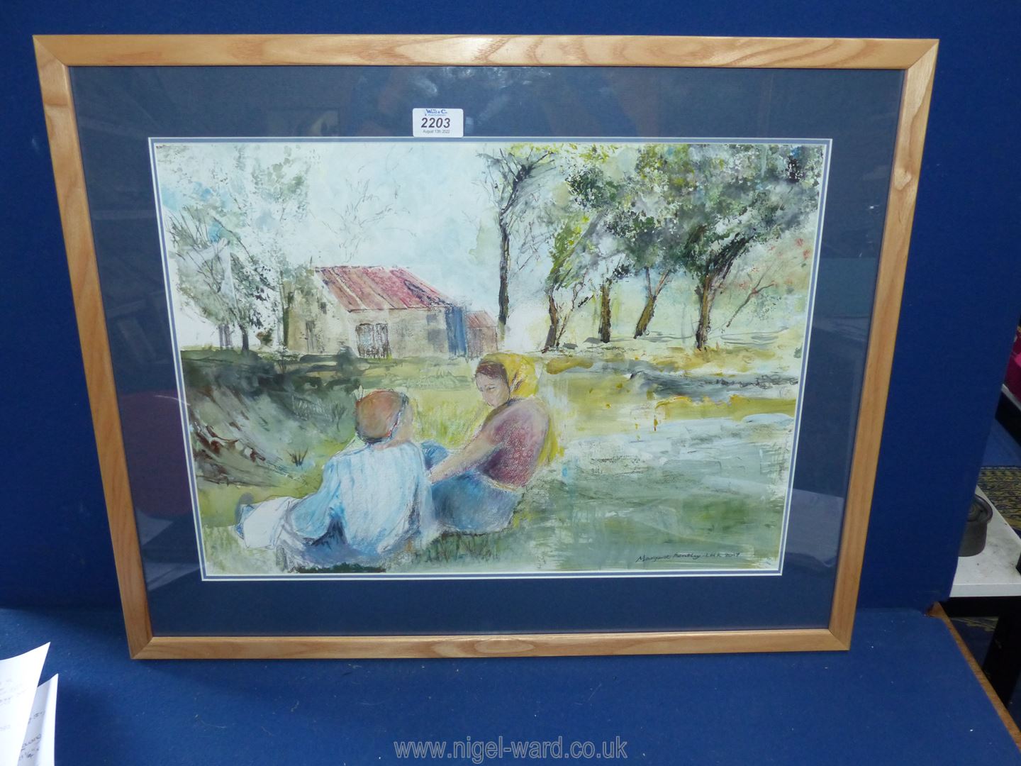 A pine framed and mounted mixed media Painting depicting two figures sat on grass with a barn and - Image 2 of 2