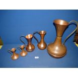 Five copper graduated pitchers, various sizes.