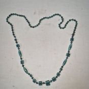 A string of vintage blue glass beads with incised Grecian style motifs, 15" long.