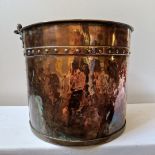 A 19th century beaten copper log/coal bin with swing handle and studded decoration in the arts and