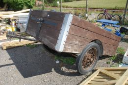A wooden trailer with vintage spoke wheels, 82" x 56".