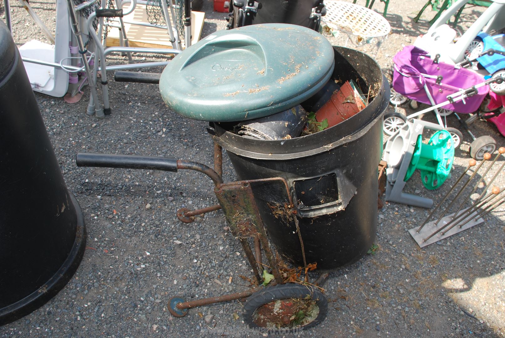 A dustbin with carrier and mixed flower pots.