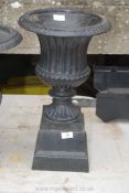 An elegant cast iron planter/urn having fluted and reeded design and an associated matching but