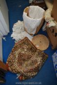 A round linen basket with lace and crochet and a small carpet.