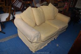 Two seater yellow covered settee with blue cushions.