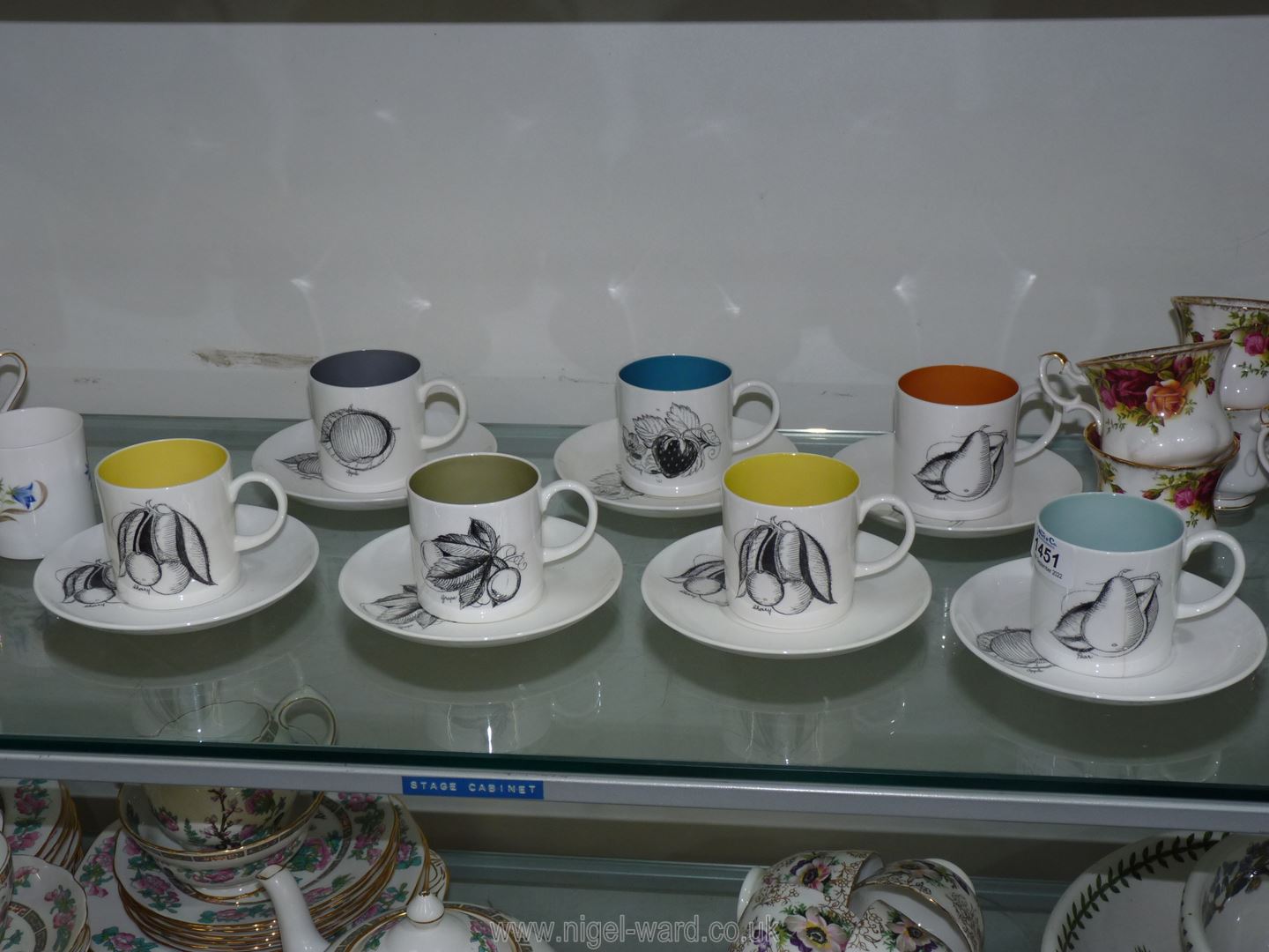 Seven Susie Cooper 'Black Fruit' coffee cans and saucers with different colour interiors,