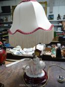 A continental porcelain table Lamp in the form of a mother and child, with fringed lamp shade,