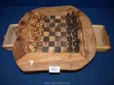 A wooden hand made chess board with two side drawers containing pieces.