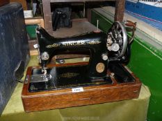 A Singer sewing machine in wooden case, hand operated and including original accessories.