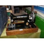 A Singer sewing machine in wooden case, hand operated and including original accessories.