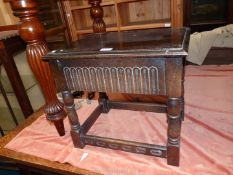 A low dark Oak Occasional Table standing on turned legs and having a fluted fronted drawer to the