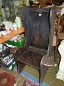 A very rustic dark stained peg joyned lambing style Armchair having a small shelf incorporated to