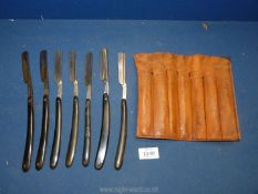 Seven antique cut throat razors in an old leather roll.