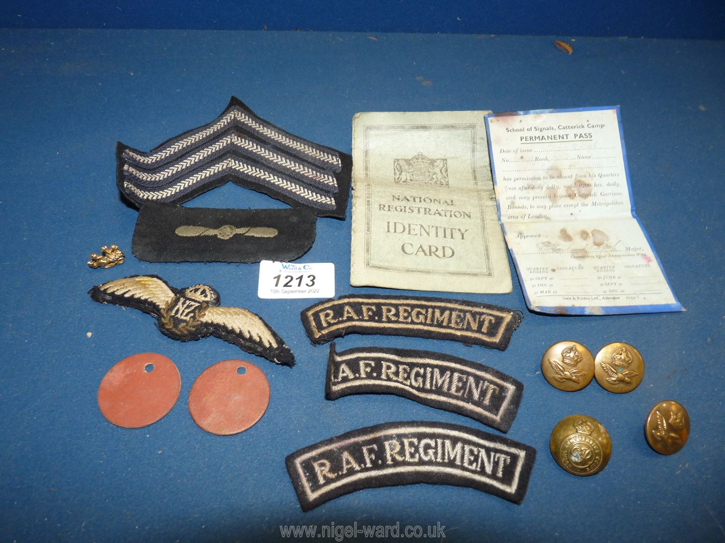 A WWII New Zealand pilot's wings and other air force badges with an identity card and a permeant