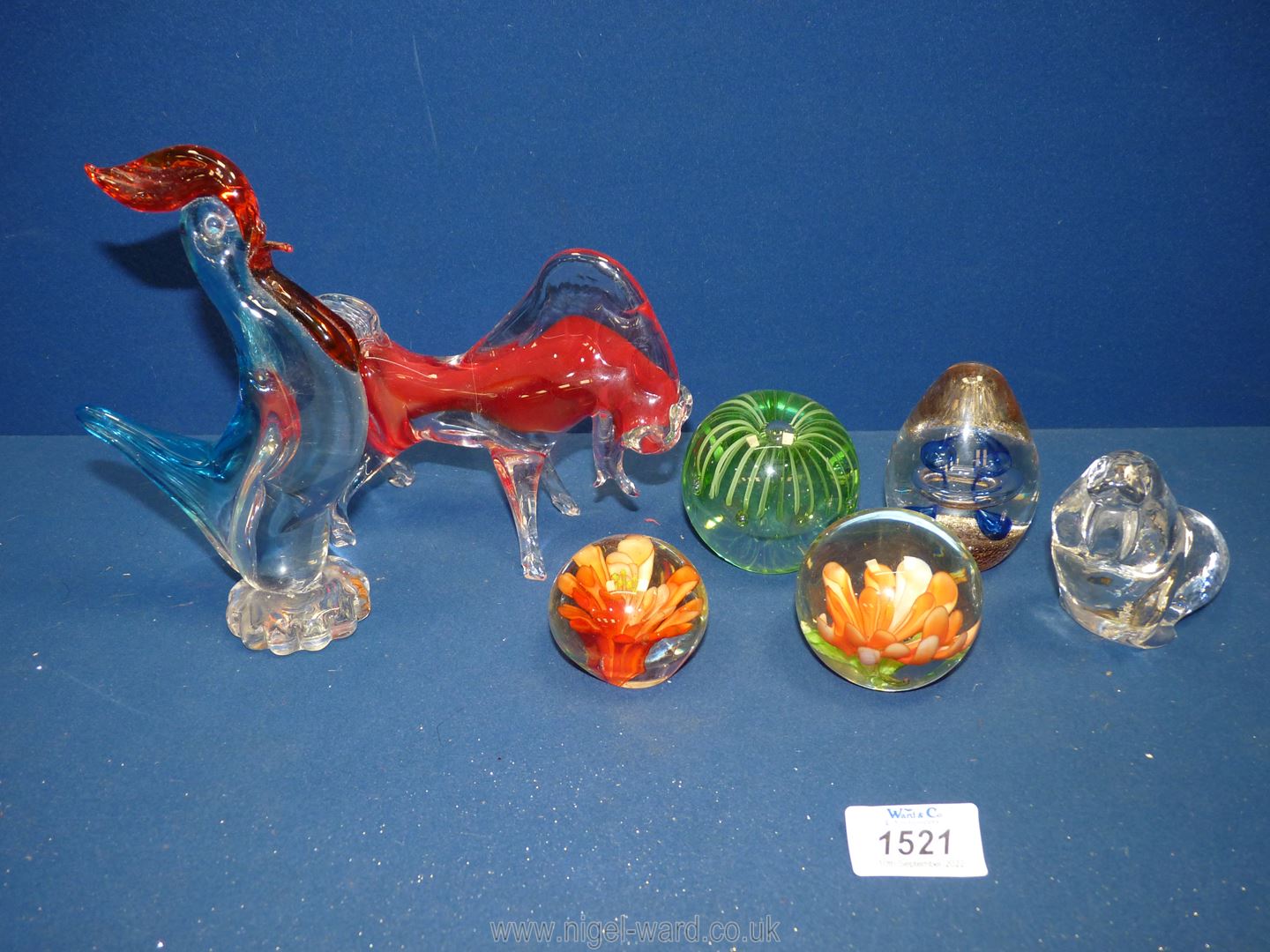 A small quantity of glass paperweights to include two with orange flowers, crystal walrus,