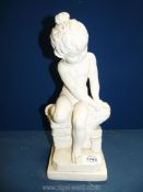 A plaster figure of a child sat on a wall, 13" tall.