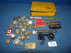 A tin of military buttons, cap badges, ribbons, cartridges, Red Cross badge, etc.