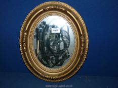 A small oval gilt framed mirror, some damage to the gilding.