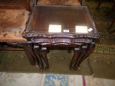 A Nest of three dark Mahogany framed Occasional Tables with carved details and inset glass tops