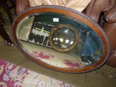 An oval, framed, bevelled edge mirror with carved border, 33 1/2" x 23 1/2".