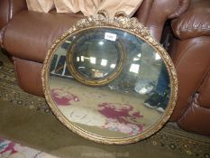 A circular gilt framed mirror with bow and rosette decoration, 21 1/4" x 23" high.