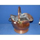 A copper coal scuttle with brass hinge and side handle.
